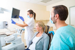 Arzt und Mitarbeiterin kümmern sich um eine Patientin im Behandlungsstuhl