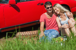 Junges Paar mit Picknick vor dem Auto
