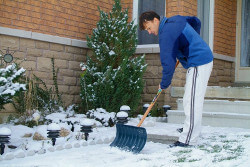 Ein Mann schippt im Hof Schnee.